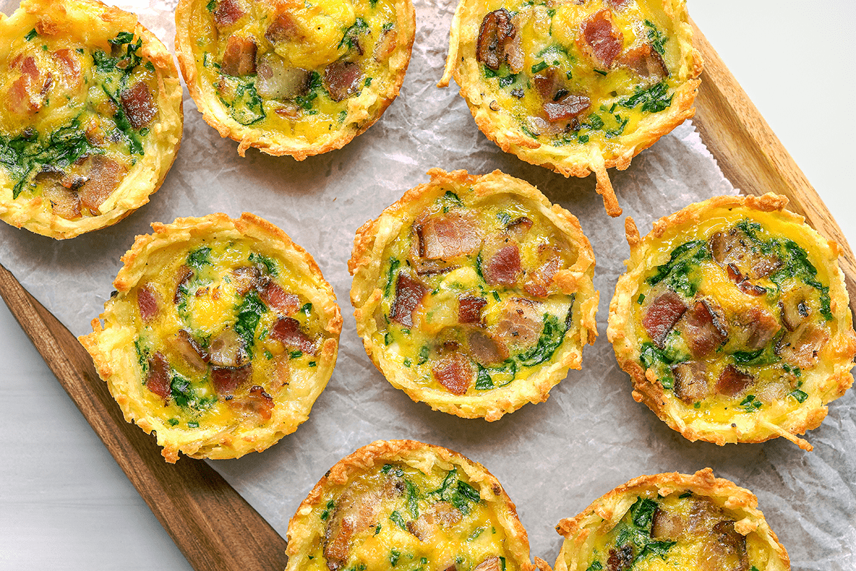 Overhead shot of Hash Brown Quiche Cups, served on wooden tray