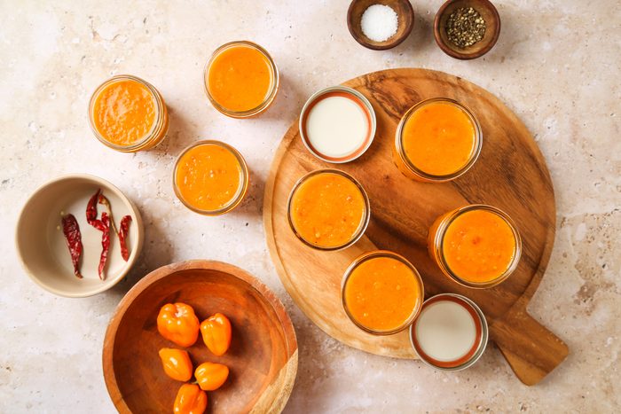 Overhead shot of Carefully ladle mixture into hot half-pint jars; leaving 1/2-inch headspace; Remove air bubbles and adjust headspace if necessary by adding hot mixture; Wipe rims; Center lids on jars; screw on bands until fingertip tight; round wooden board; marble surface;