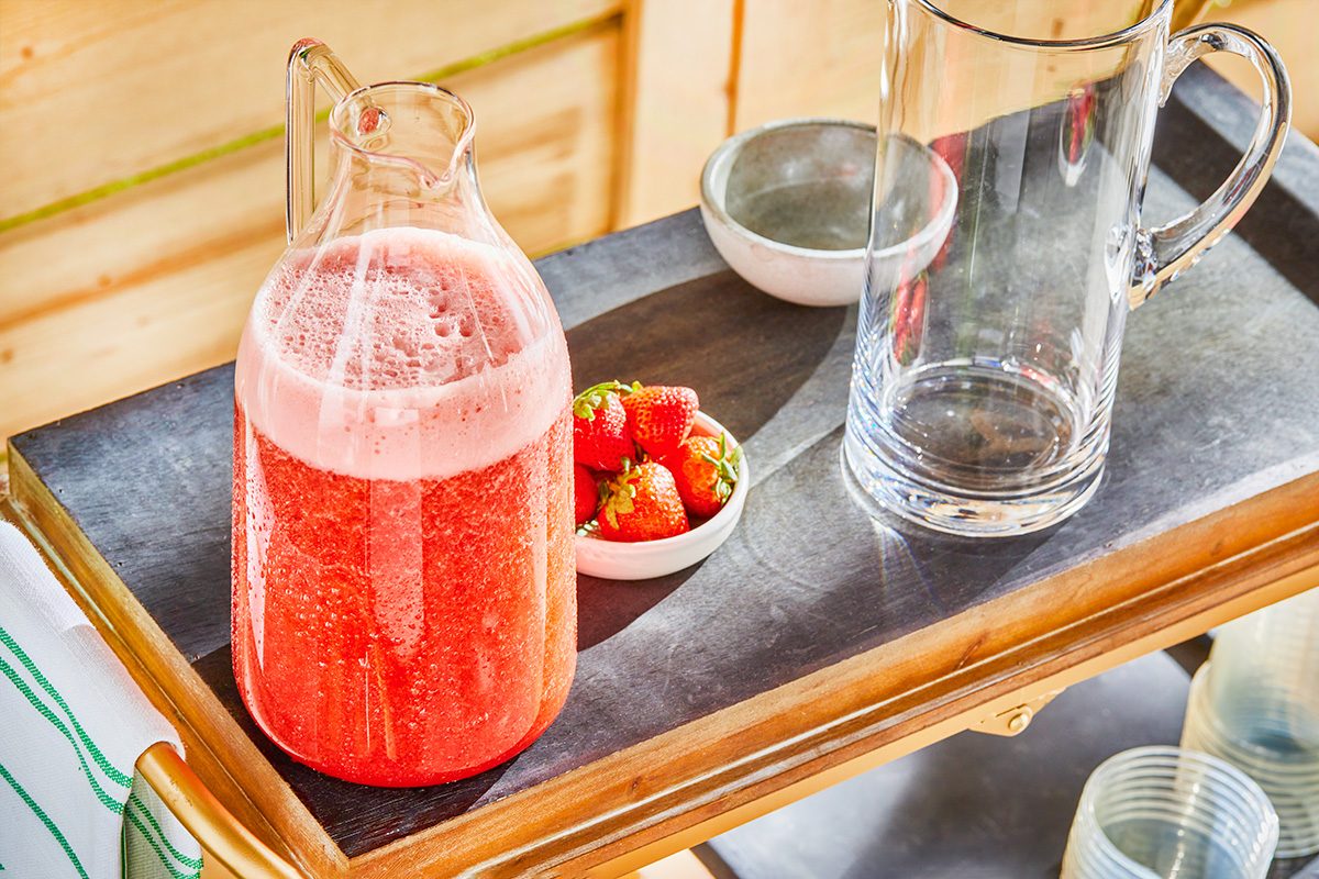 Strawberry drink and raw strawberries are on table for outdoor drink station setup