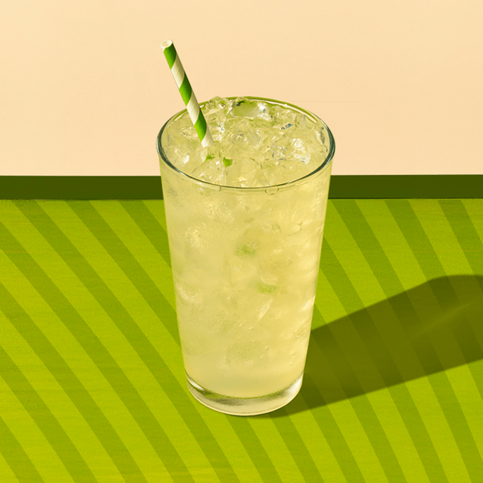 Green lemonade drink on ice on a green background