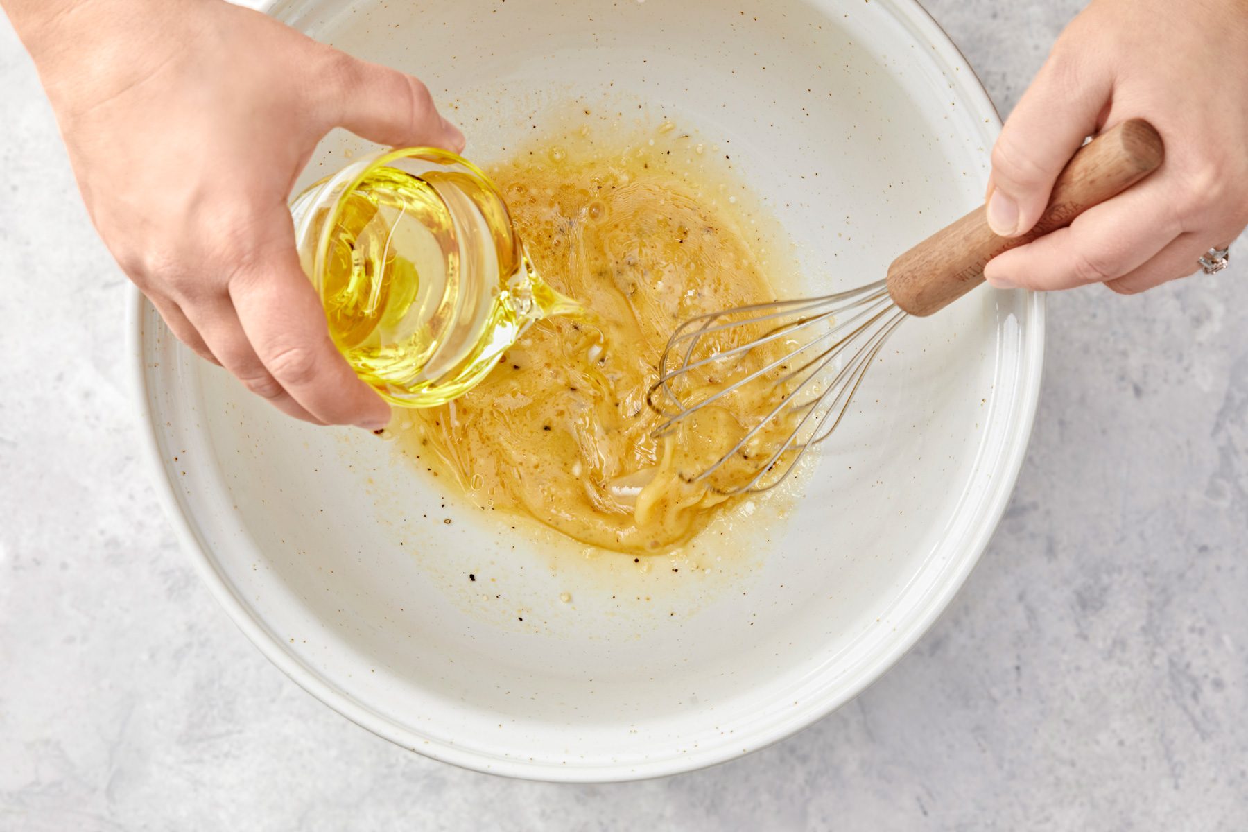 overhead shot of a large white bowl, Whisking in olive oil into ingredients