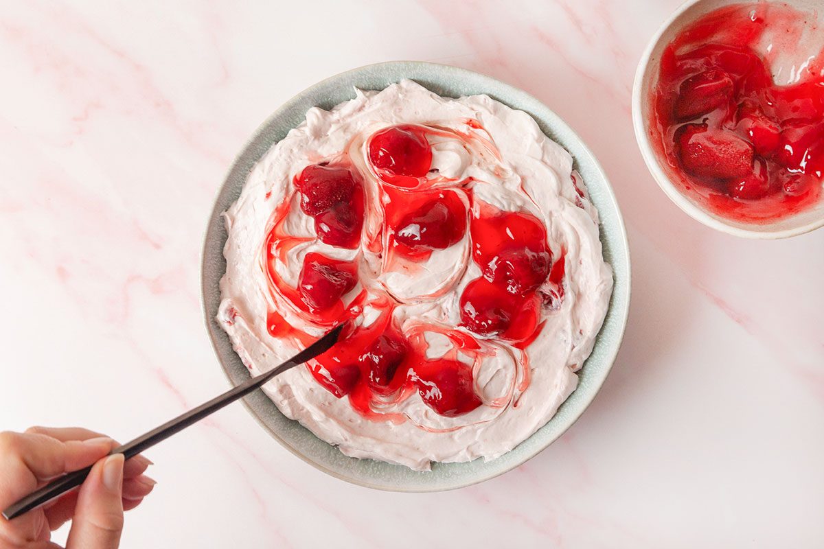 Cream cheese mixture in a bowl and strawberry filling top on it