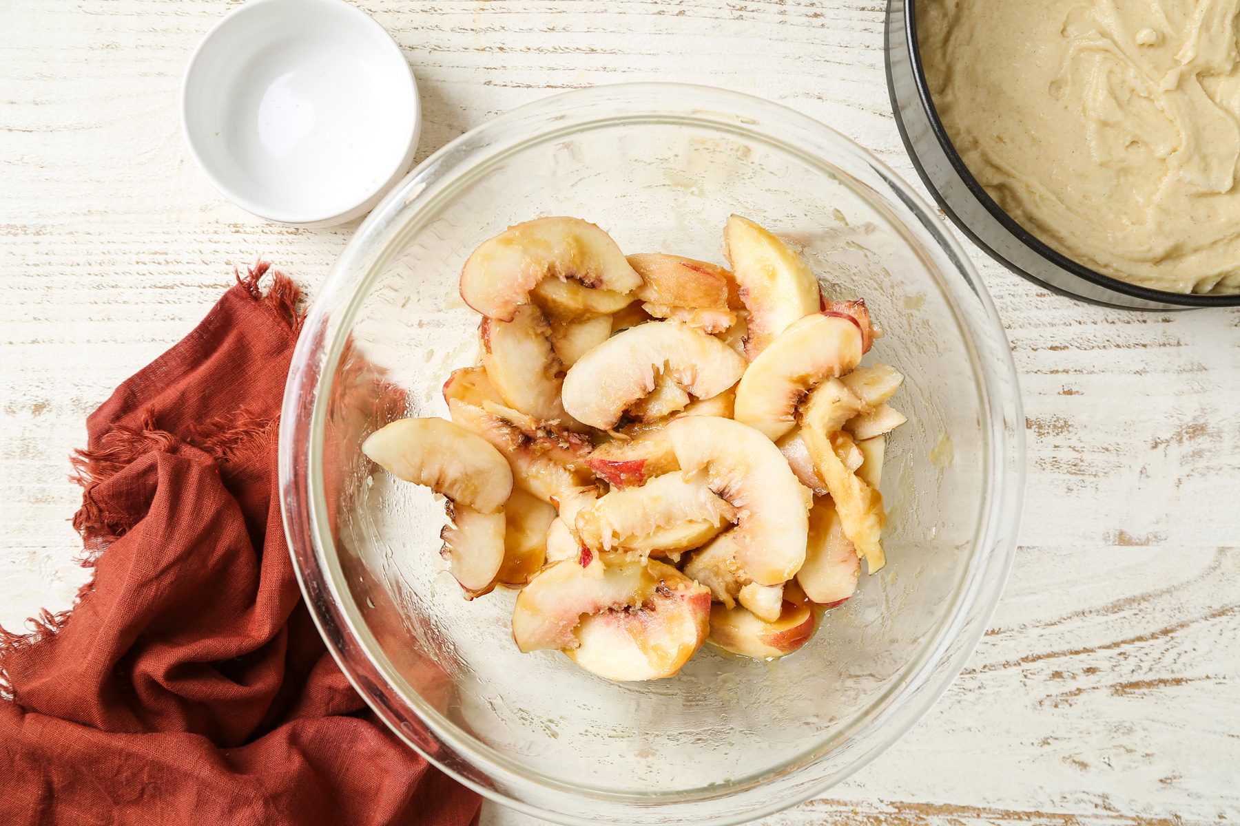 Overhead shot; a large bowl, stir together brown sugar and butter to form a wet paste; Stir in peaches; Spoon peach mixture evenly over top of cake batter; Bake until a toothpick inserted in the center comes out clean 40-45 minutes; napkin; white wooden surface;