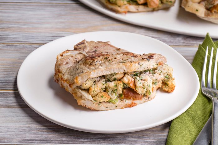 Front shot of Air Fryer Stuffed Pork Chops in a white plate on a wooden table top
