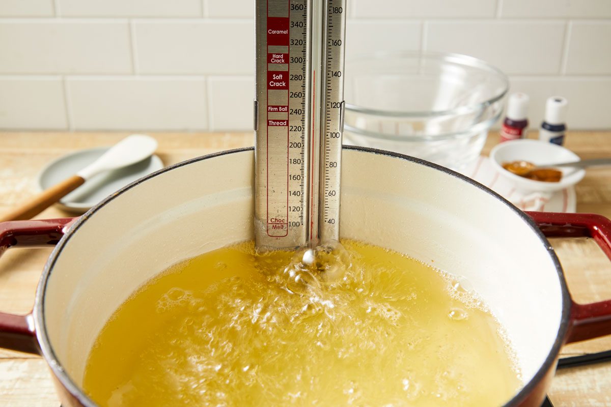 Close-up shot of a large heavy saucepan; combine the sugar; water and corn syrup; Cook and stir over medium heat until sugar is dissolved; Bring to a boil; Cook without stirring until a candy thermometer reads 290 degree;