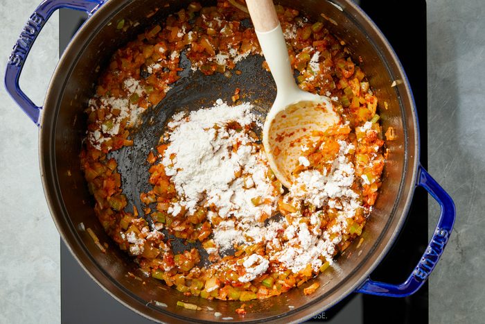 Overhead shot of the same saucepan; Stir in flour; cook until browned 1-2 minutes; induction; spoon; grey surface;