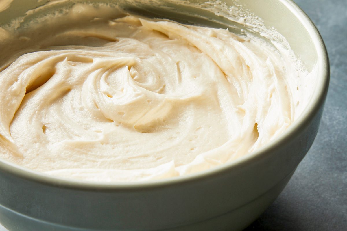 closeup shot of Cream Cheese Frosting in a bowl placed over dark gray background