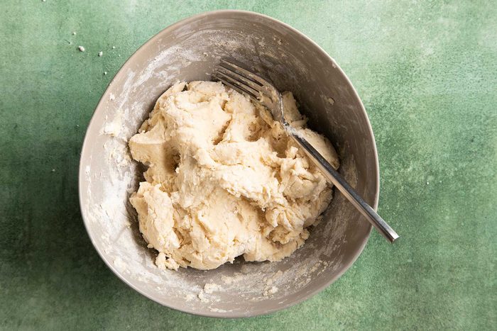 Overhead shot of flour mixture kept in white bowl kept on top of a green marble countertop.