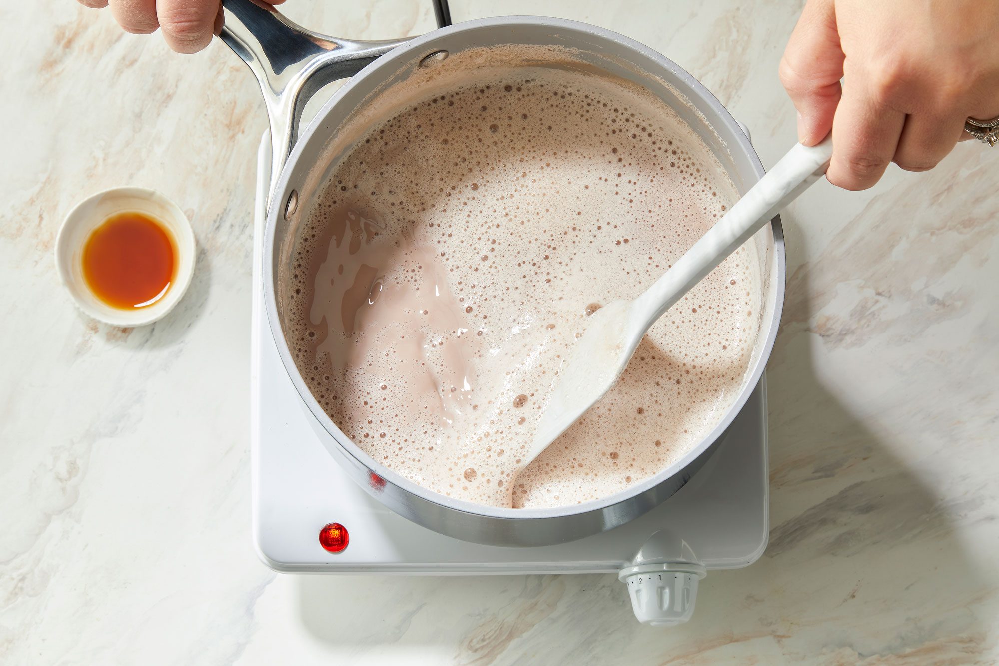 Overhead shot of the same saucepan; Cook and stir over medium heat until marshmallows are melted about 8 minutes; induction; spatula; marble surface