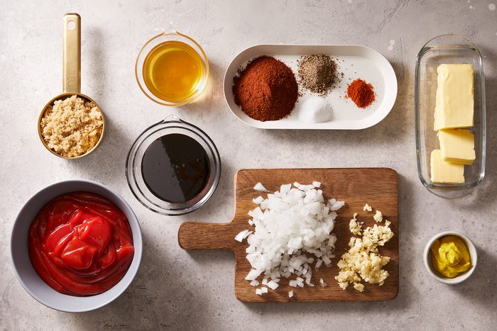 Overhead shot of all ingredients on the kitchen counter required to make Kansas City Barbeque BBQ sauce on a white-grey marble countertop.