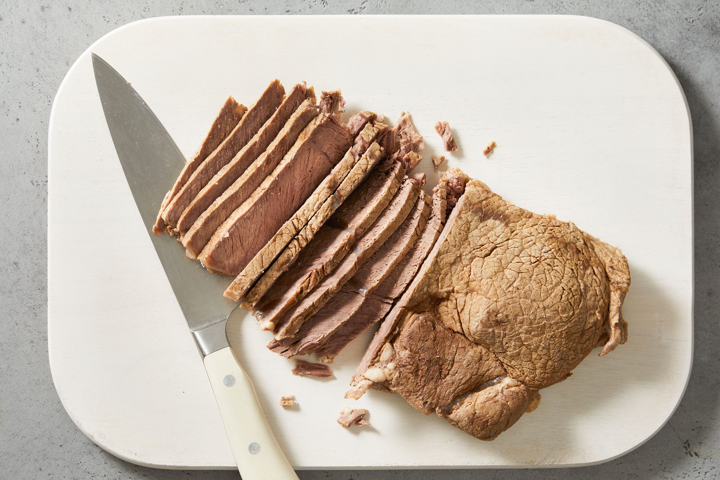 thinly sliced refrigerated beef on a counter with a knife on side