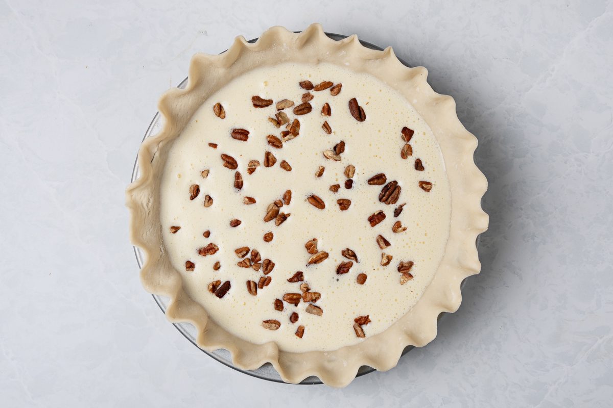 pecans sprinkled over cream cheese mixture layered over pie crust