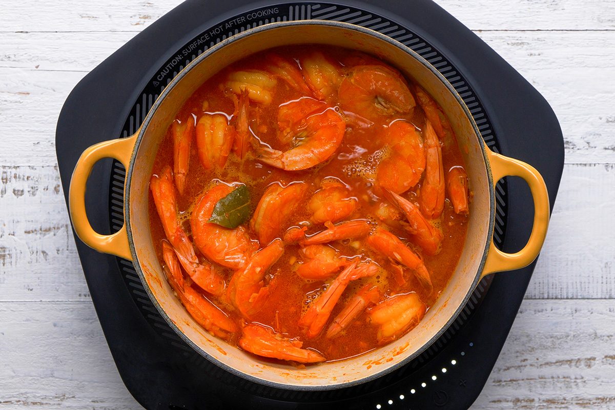A pot of food on a table, prepared with ketchup and parsley, awaiting serving alongside hot cooked rice.