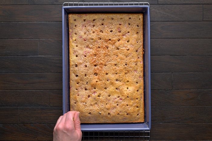 overhead shot of a golden brown baked cake; Use the bottom of a wooden spoon to poke holes in the top of the cake