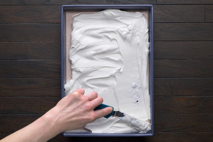 overhead shot of a rectangular baking tray filled with a smooth layer of white whipped cream or frosting
