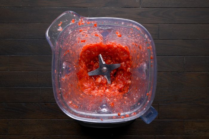 overhead shot of a blender jar filled with a chunky mixture of red strawberries