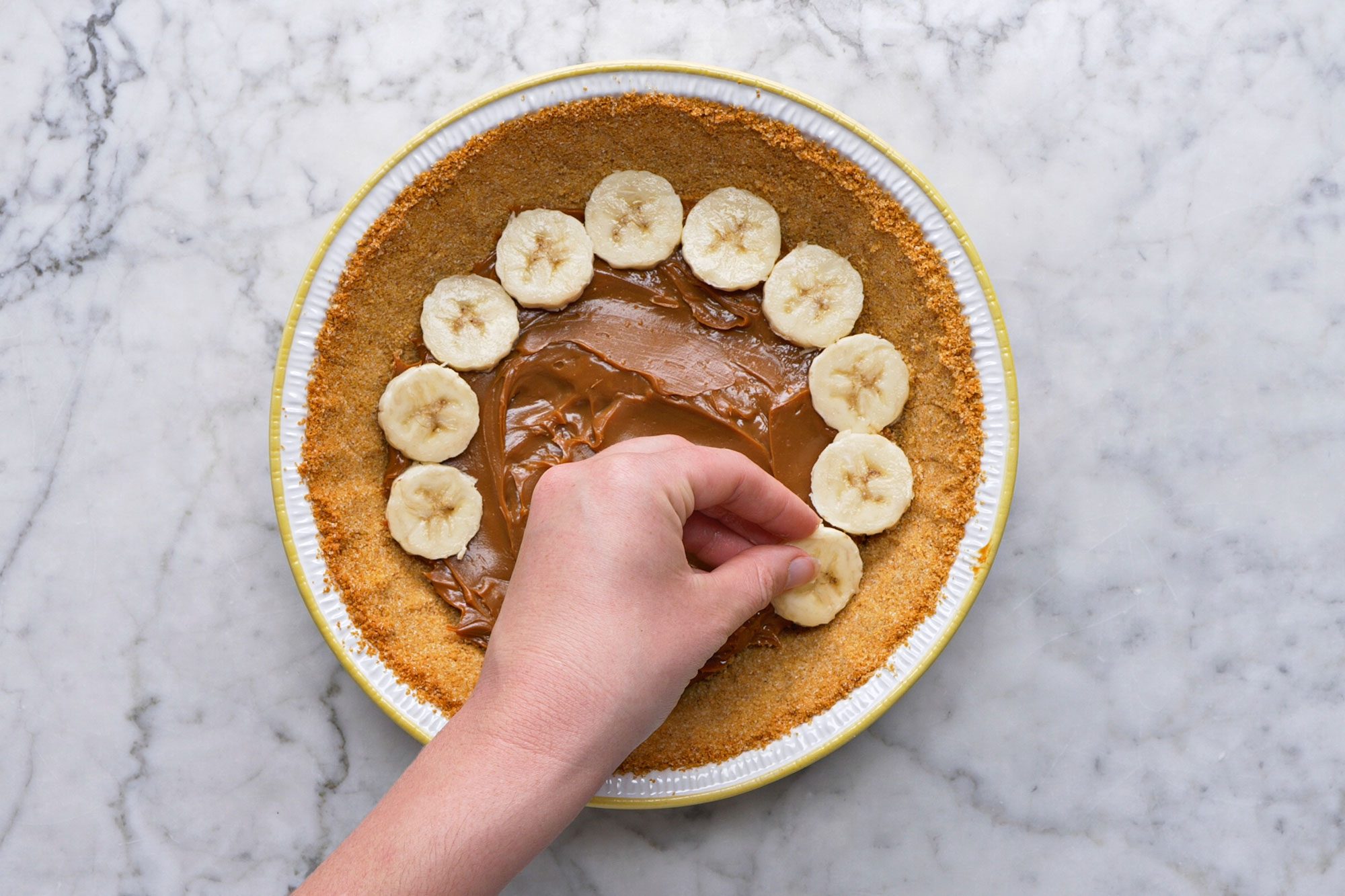 Overhead shot of Top with two layers of sliced bananas; on a marble textured surface