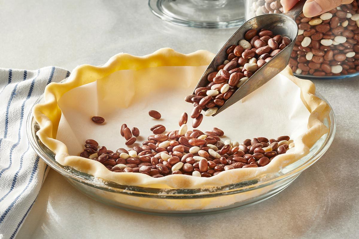 Dry beans are being added to the pie crust