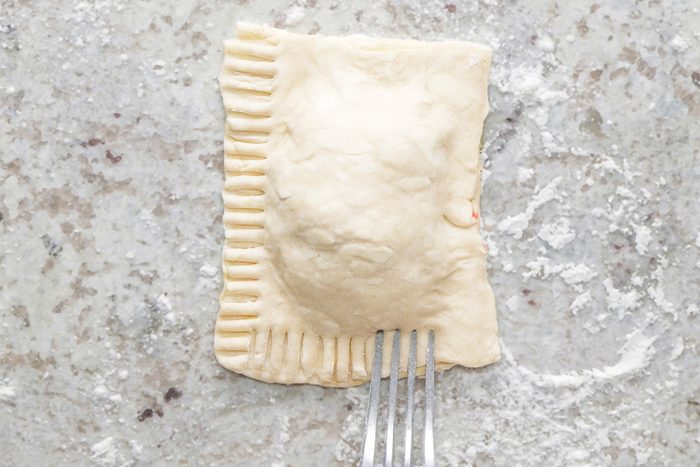 Pressing the edges together with a fork’s tines to seal