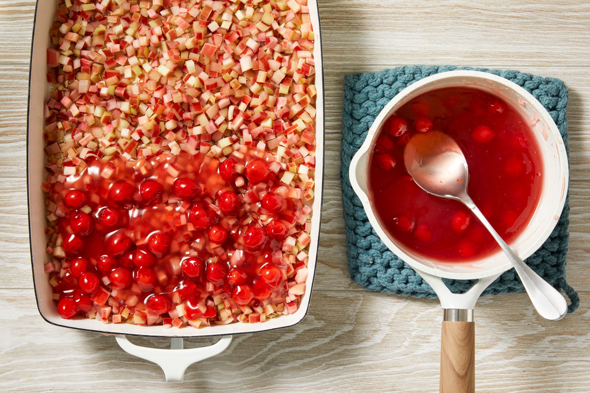 Overhead shot; remove saucepan; stir in extract and cherry pie filling; spoon over rhubarb; cream wooden surface