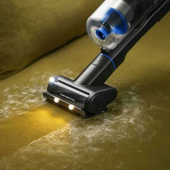 Bissel Vacuum with headlights vacuuming up pet hair on a green couch