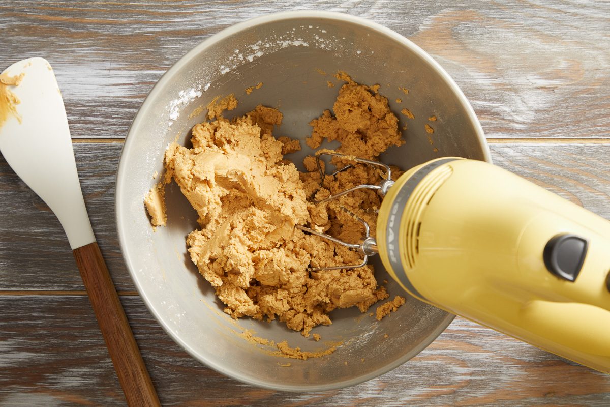 peanut butter, confectioner's sugar, butter and vanilla extract being beaten togther in a bowl with a handheld mixer