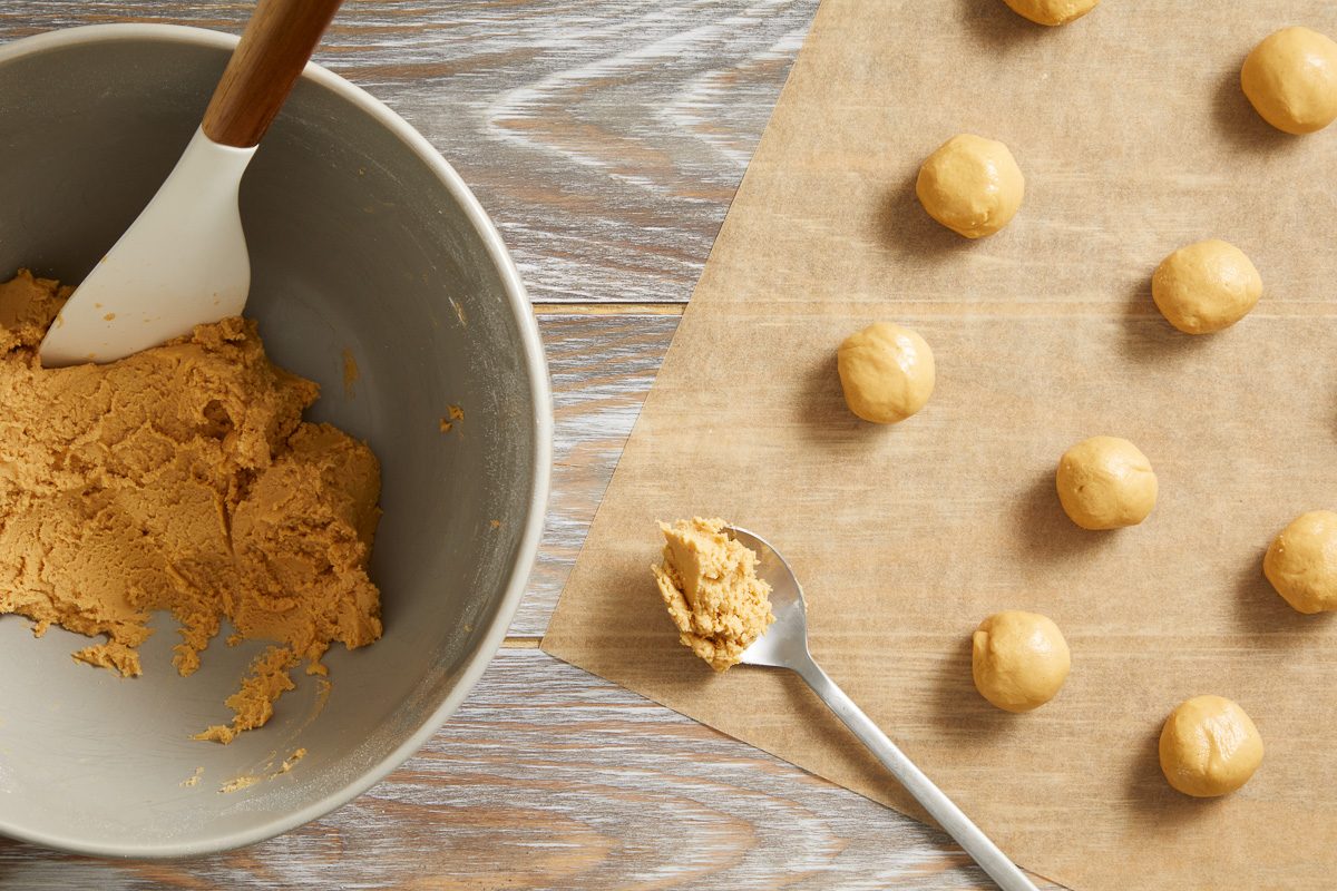 Peanut Butter mixture rolled into balls arranged on waxed paper-lined baking sheet