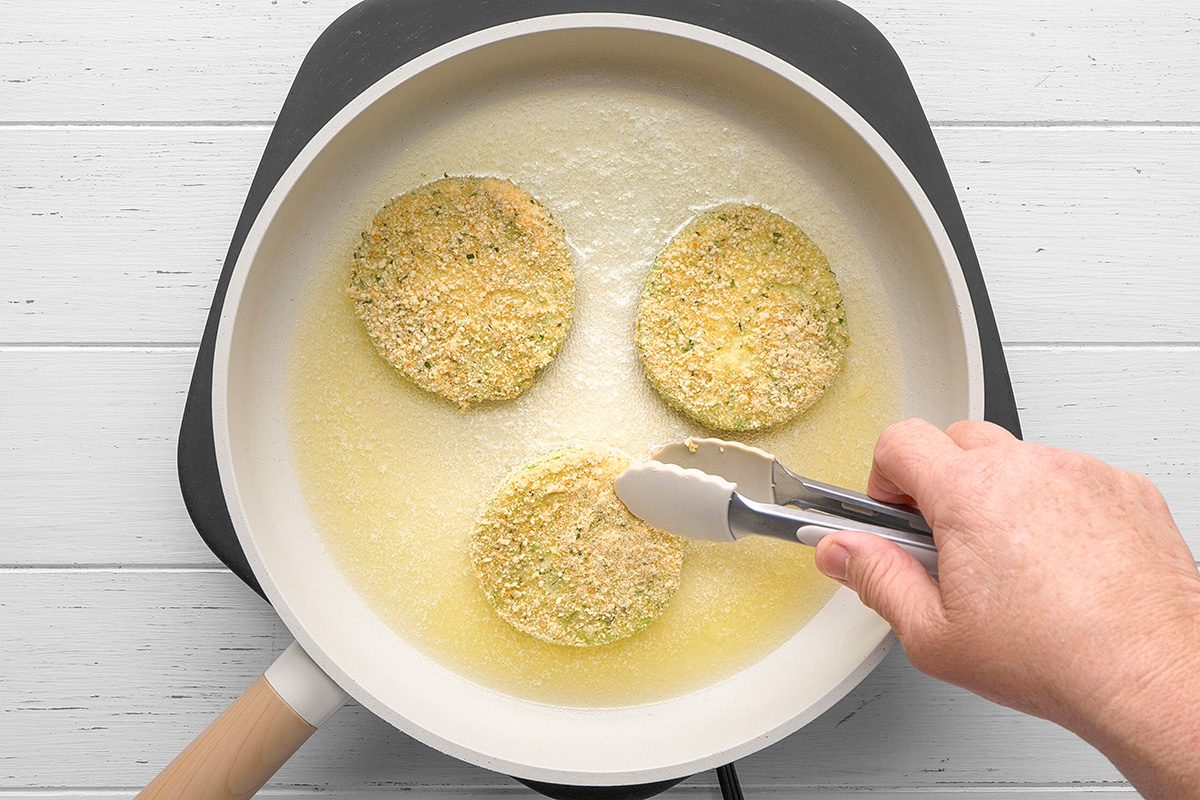 In a skillet, heat butter and oil over medium-high heat. Fry tomatoes until brown on both sides but firm enough to hold their shape