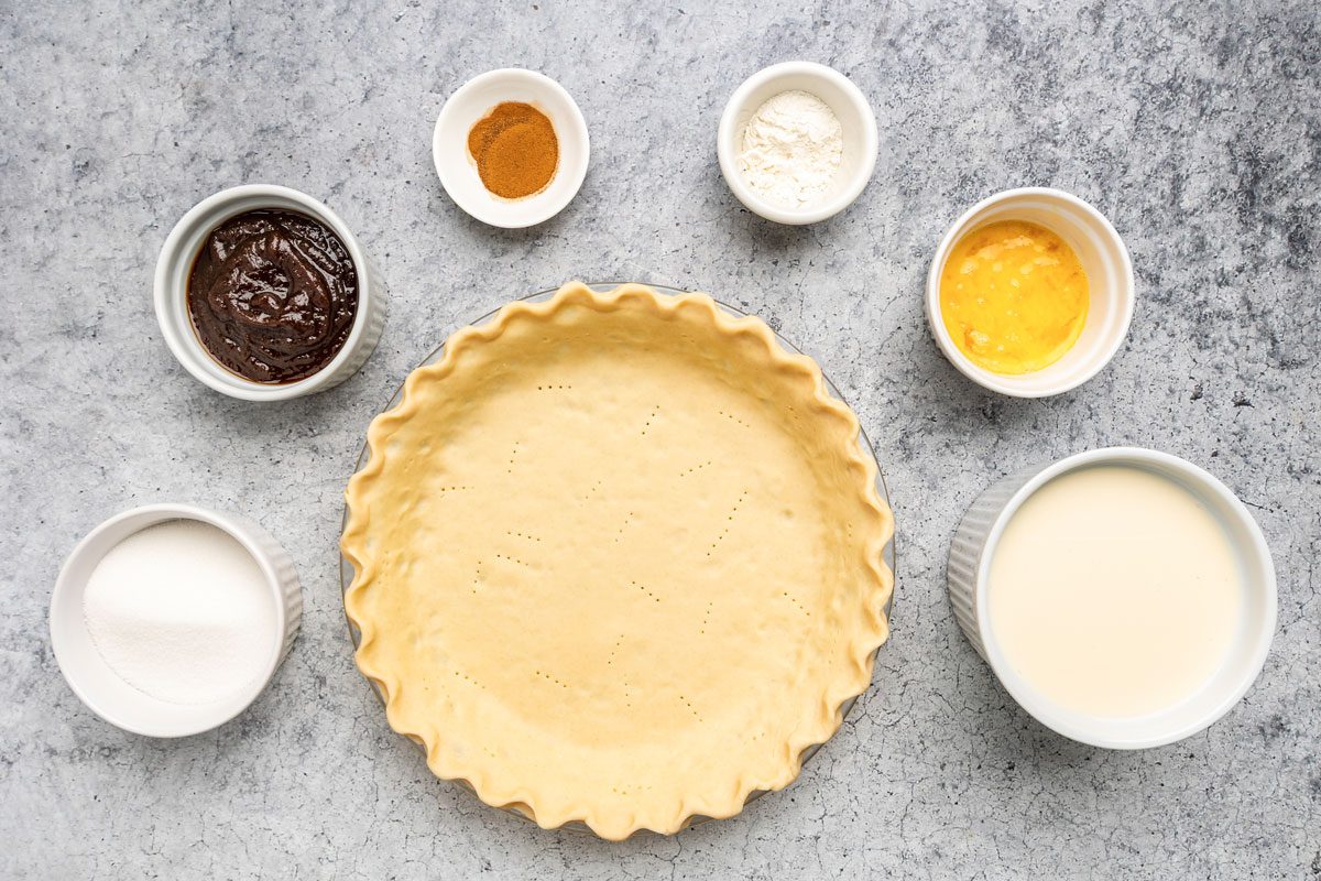 Overhead shot of all ingredients for Apple Butter Pie on a grey marbel surface;