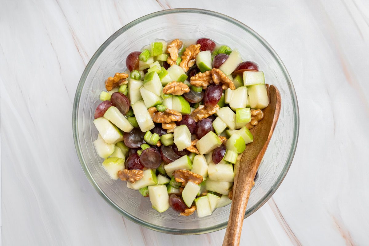 Overhead shot of the same bowl; toss gently with wood spoon; all set on a marble surface;