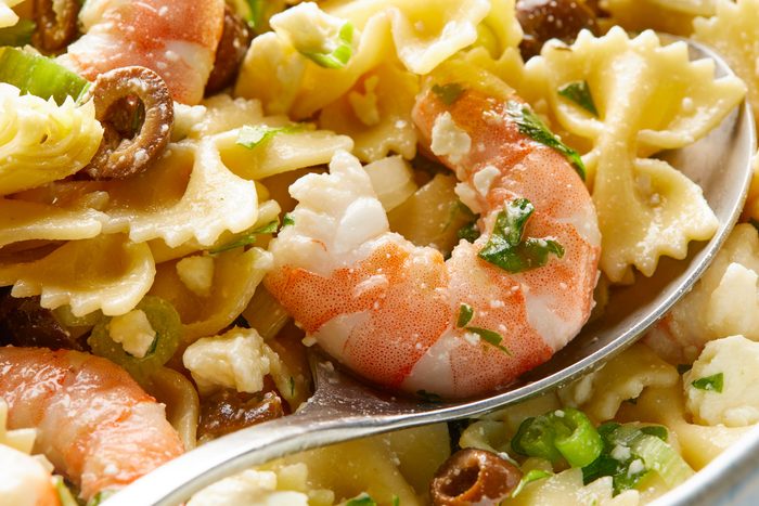 Closeup view shot of Artichoke Shrimp Pasta Salad in a large bowl with a spoon