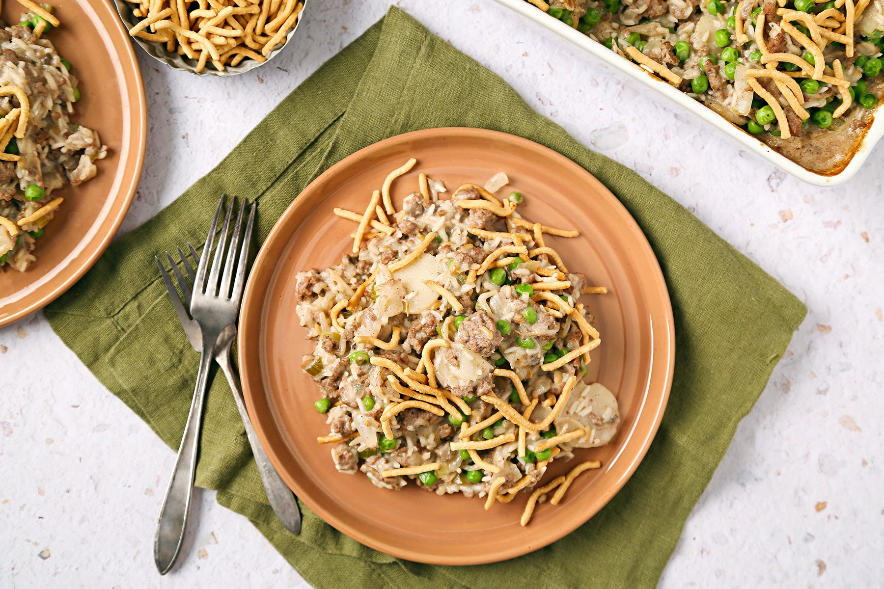 Chinese Casserole served on an orange plate with a fork kept on side. Plate is kept on an olive green kitchen cloth.