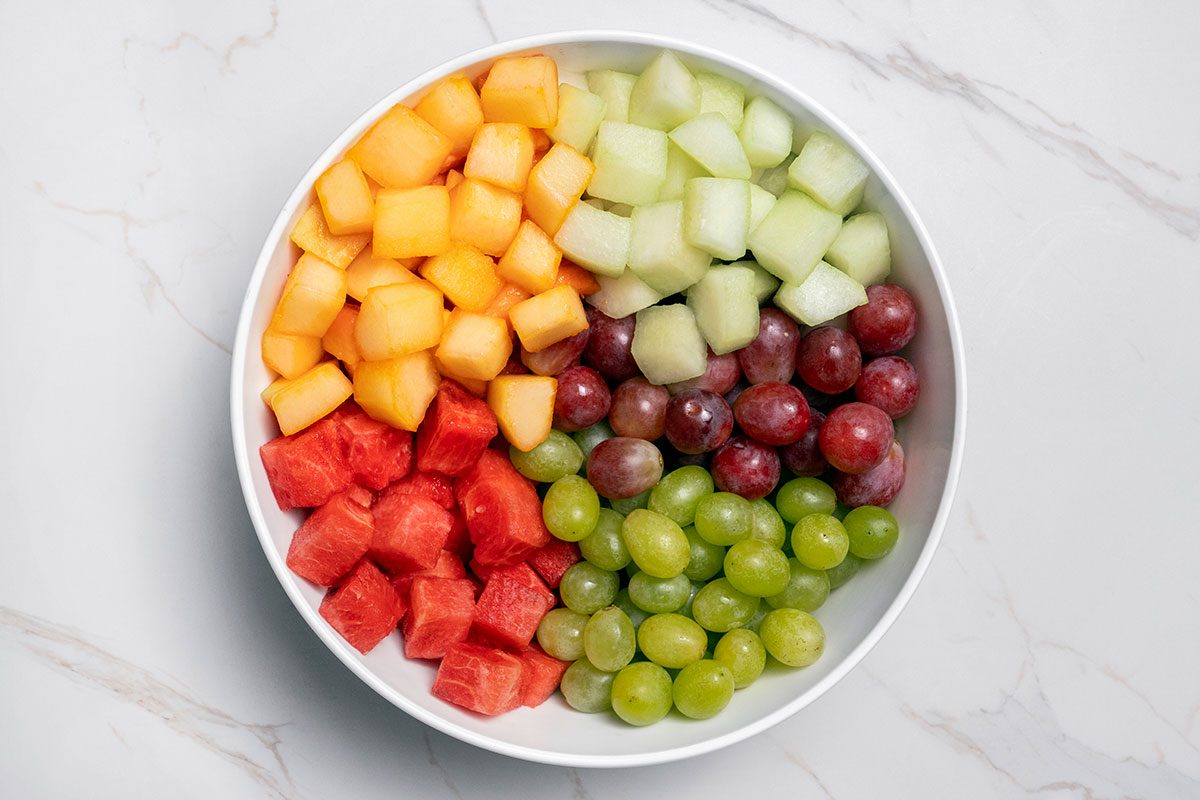 watermelon, honeydew, cantaloupe and red and green grapes in a large bowl