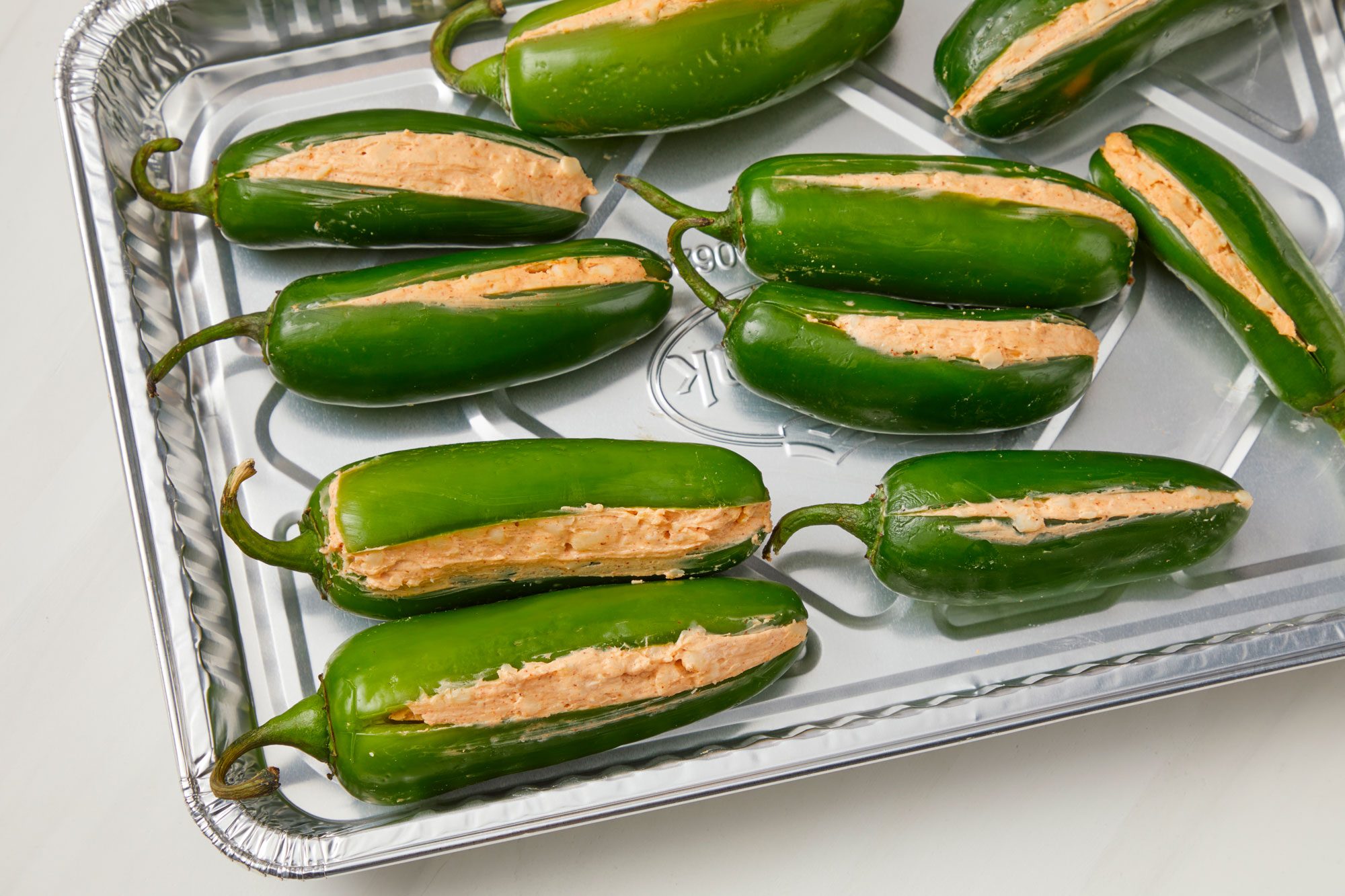 Overhead shot; In a small bowl, combine the first seven ingredients; Fill each pepper with 1 tablespoon cheese mixture; Prepare grill for indirect heat; Place peppers in a disposable foil pan; Grill, covered, over indirect medium heat for 8-10 minutes or until peppers are tender and cheese is melted; all set on a white surface