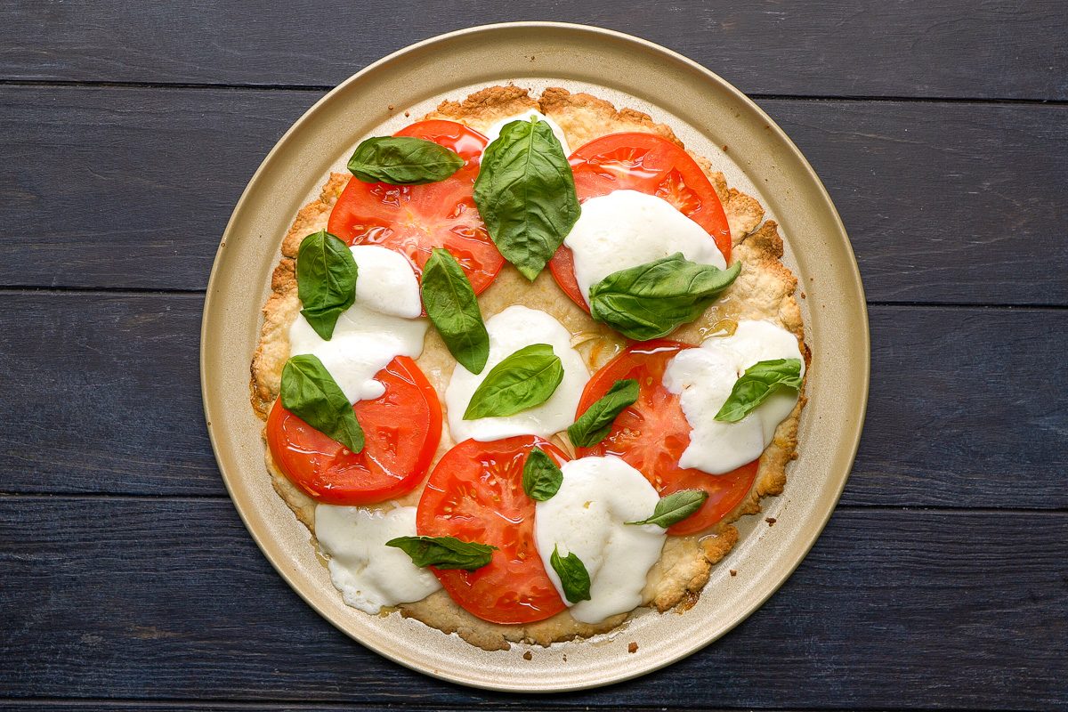 Pizza topped with basil leaves