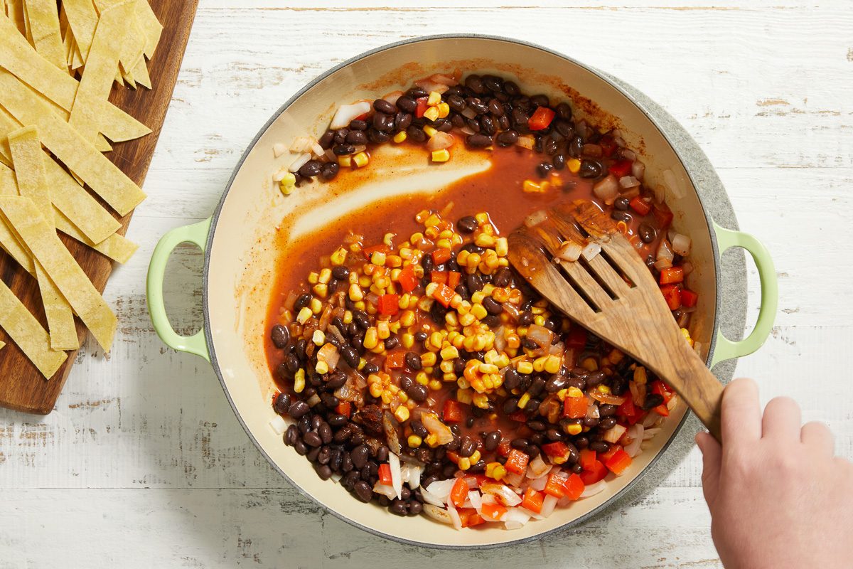 Stirring in the beans, enchilada sauce, corn, chili powder, cumin and pepper