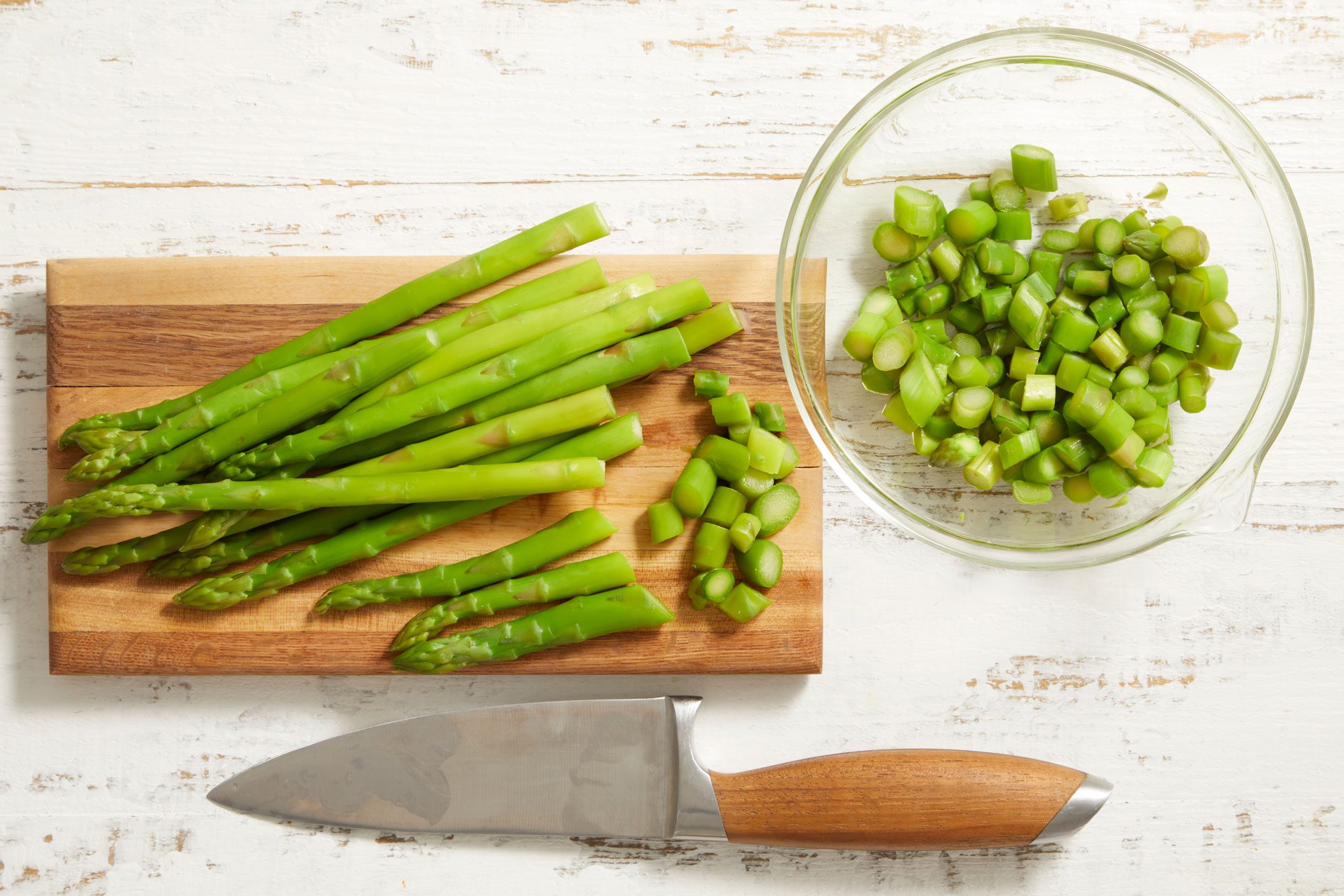 chopped Asparagus on a wooden board with knife