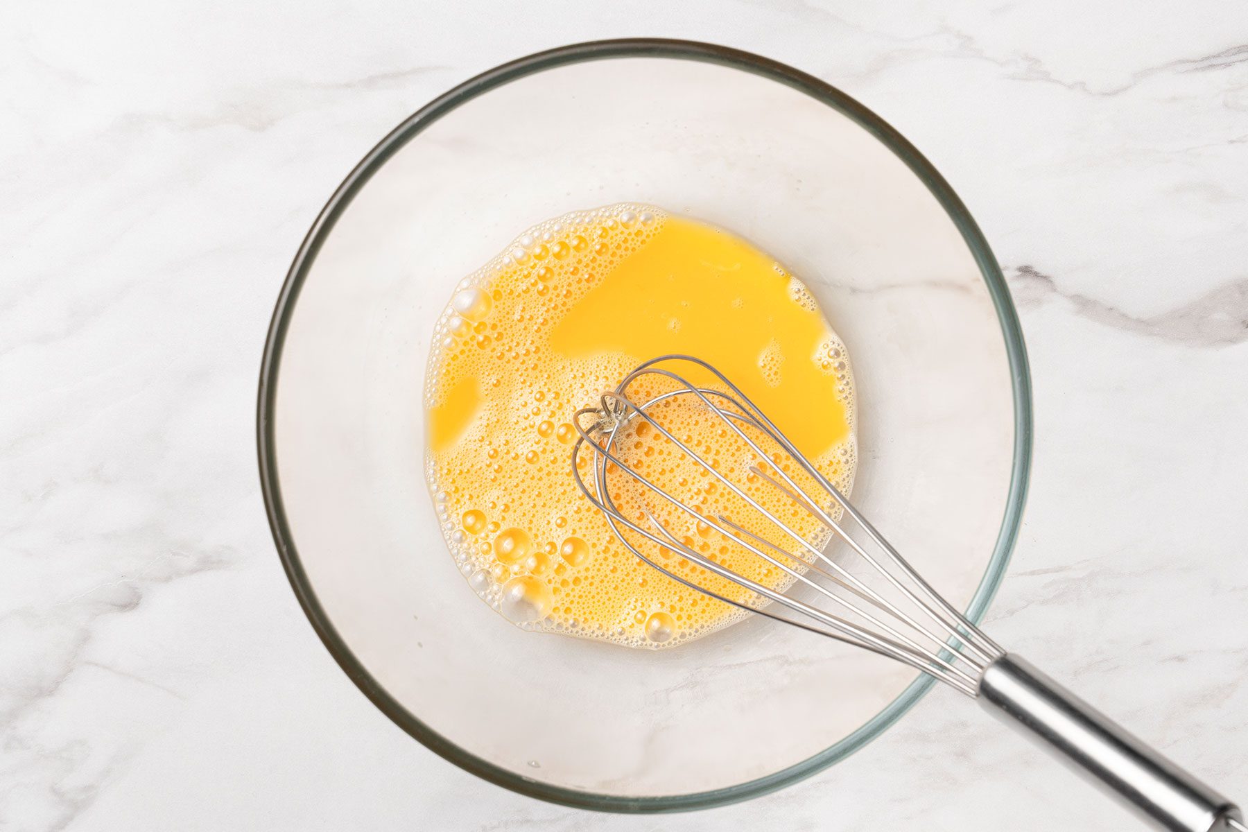 Eggs beaten in a glass bowl.