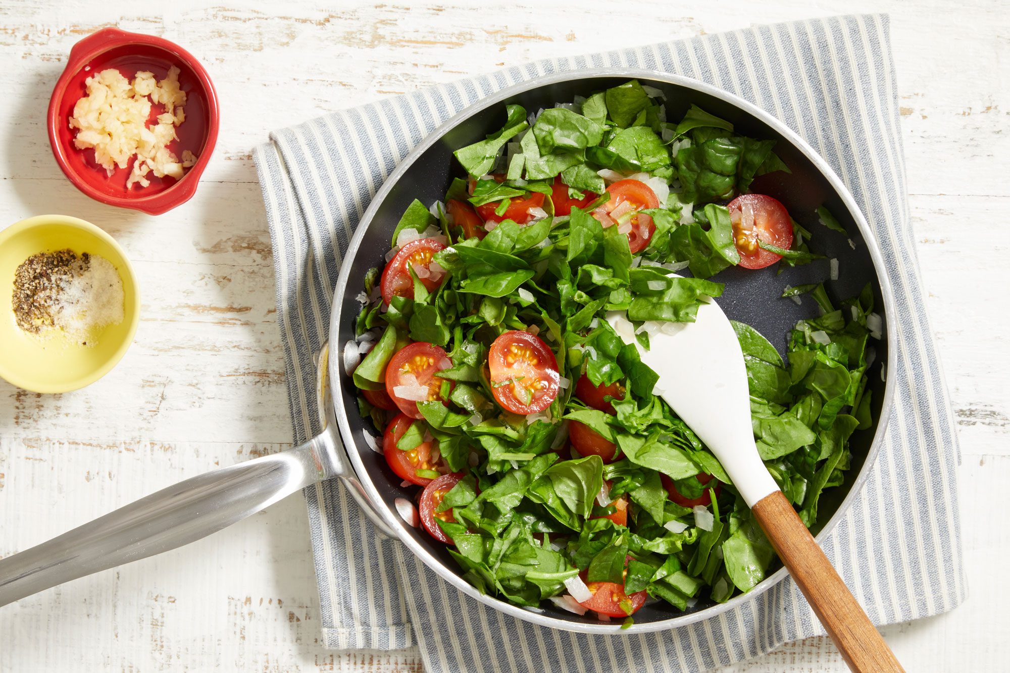 Cook the spinach, tomatoes, and onion until tender;
