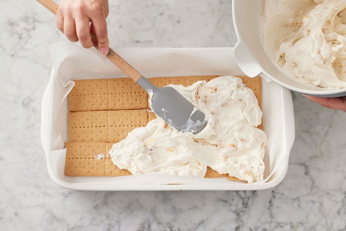 marshmallow-ice cream mixture being layered o the top of graham crackers