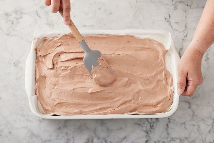 Chocolate pudding mix being layered on the top of marshmallow ice cream mix