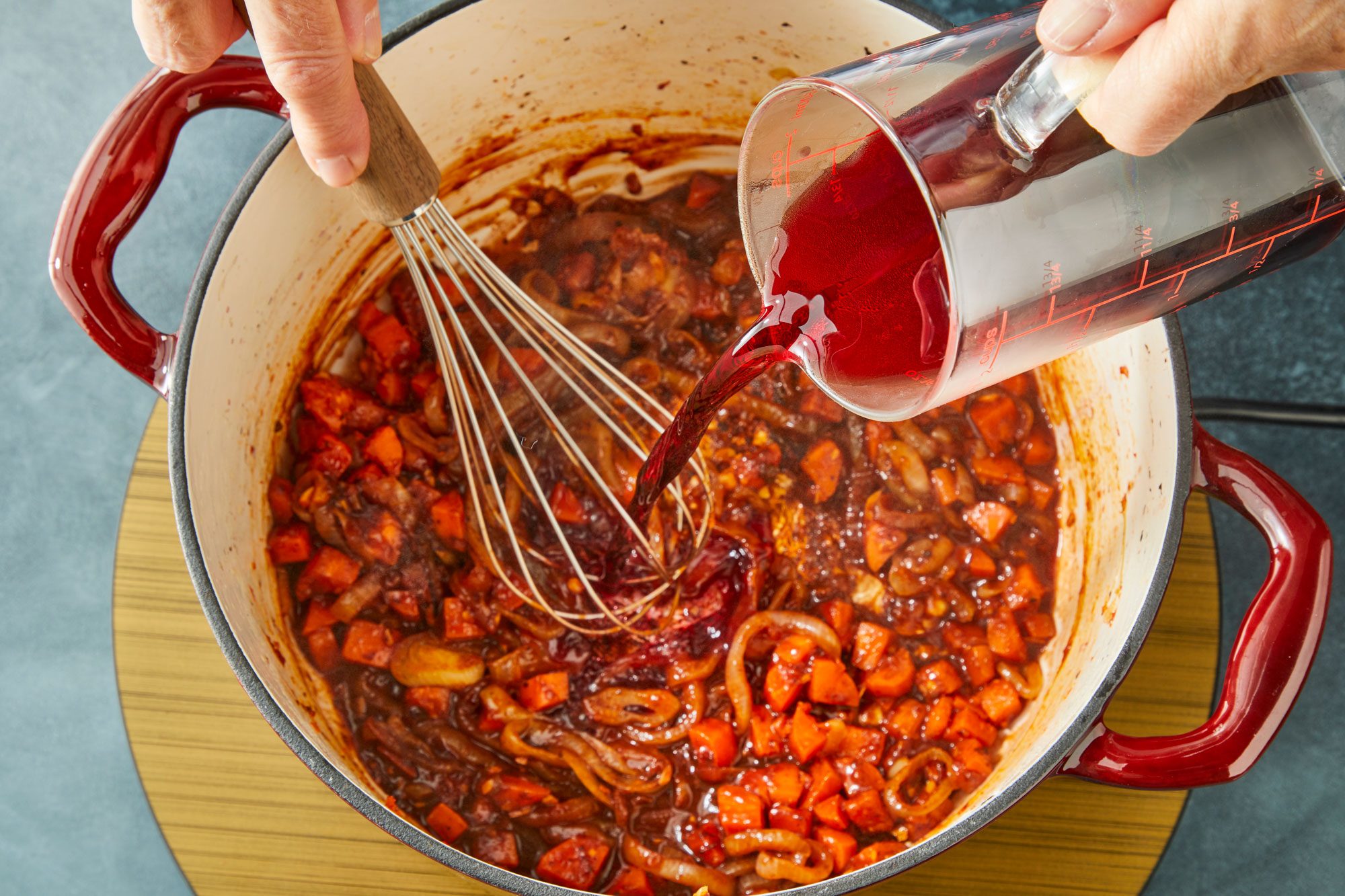 Overhead shot of slowly whisk in wine; whisk tool; induction; dark surface;