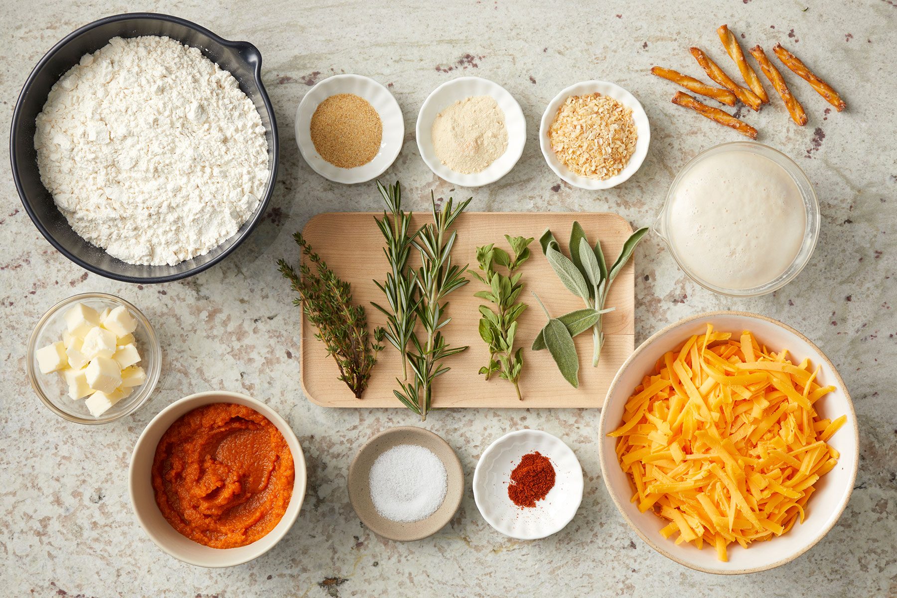 Ingredients for Pumpkin Shaped Rolls in big and small bowls and on wooden board on a counter.