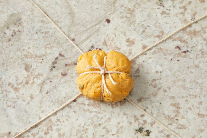 Wrapped dough ball in a kitchen string with a knot on it.