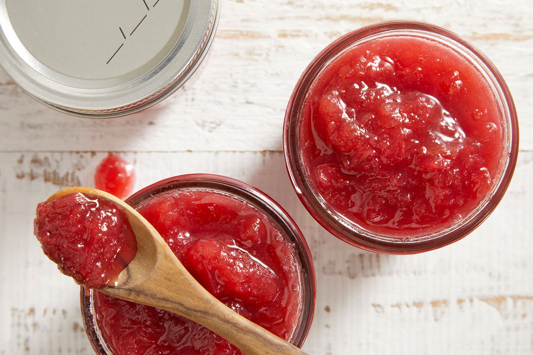 Rhubarb Pineapple Jam in glass jars with a wooden spoon kept on one of them.