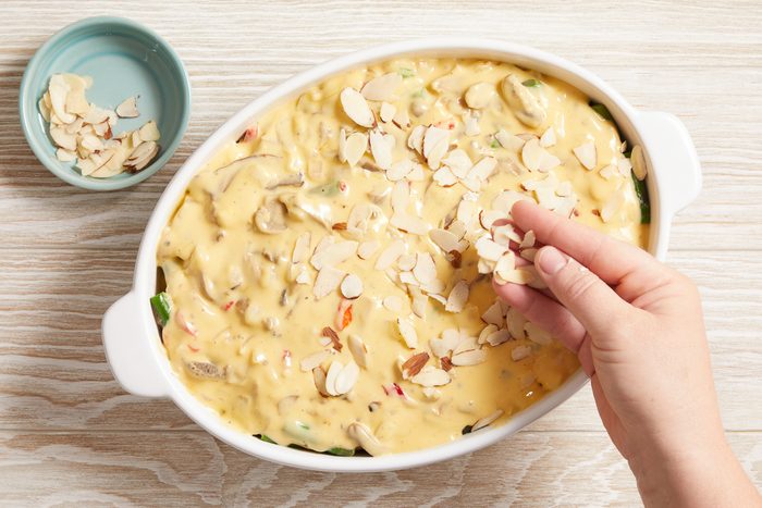 sliced almonds being sprinkled on top of casserole