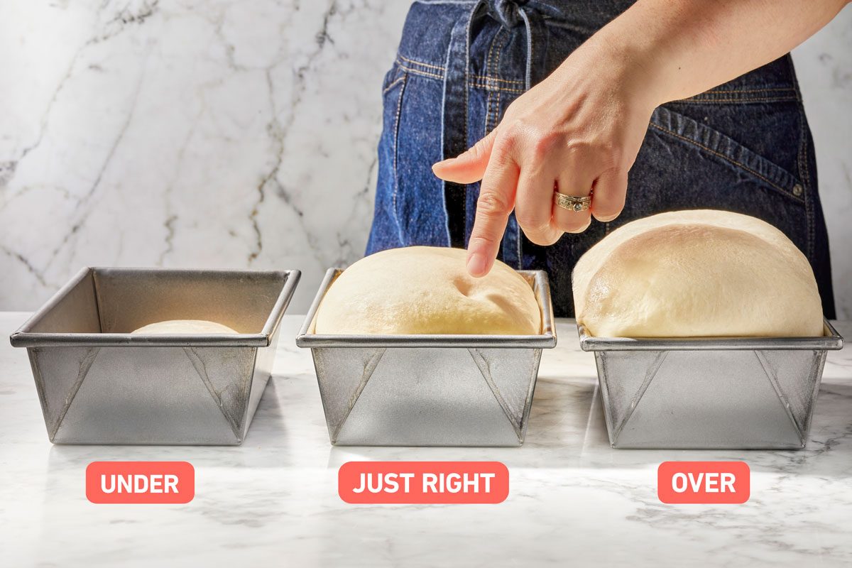 Three containers of bread dough lined up on a counter with varying degrees of doneness of proofing; a hand performs the poke test on the center one