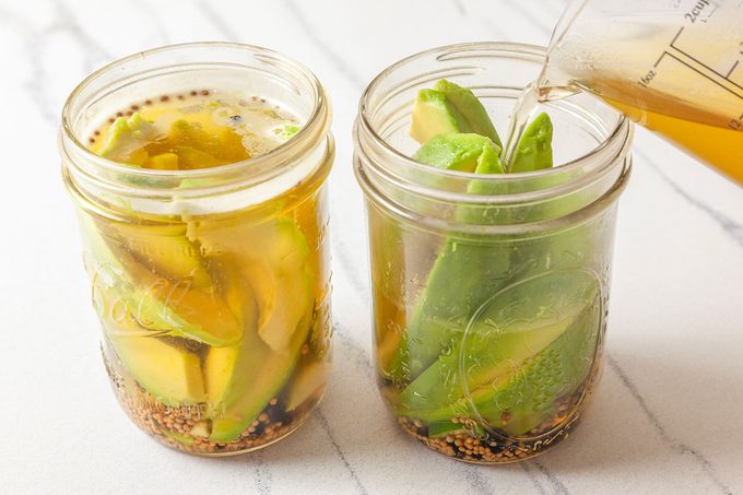 Brine poured into jars with avocados inside