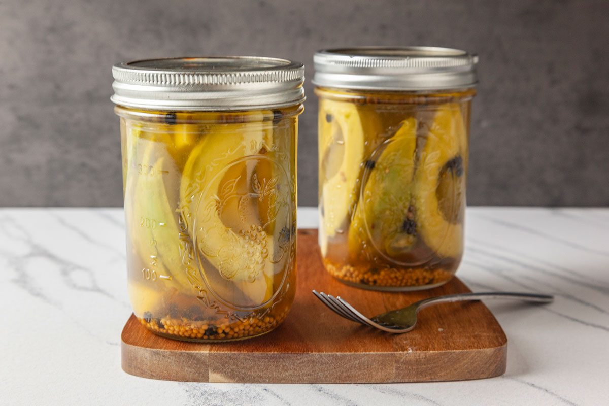Pickled Avocados with a fork on wooden board