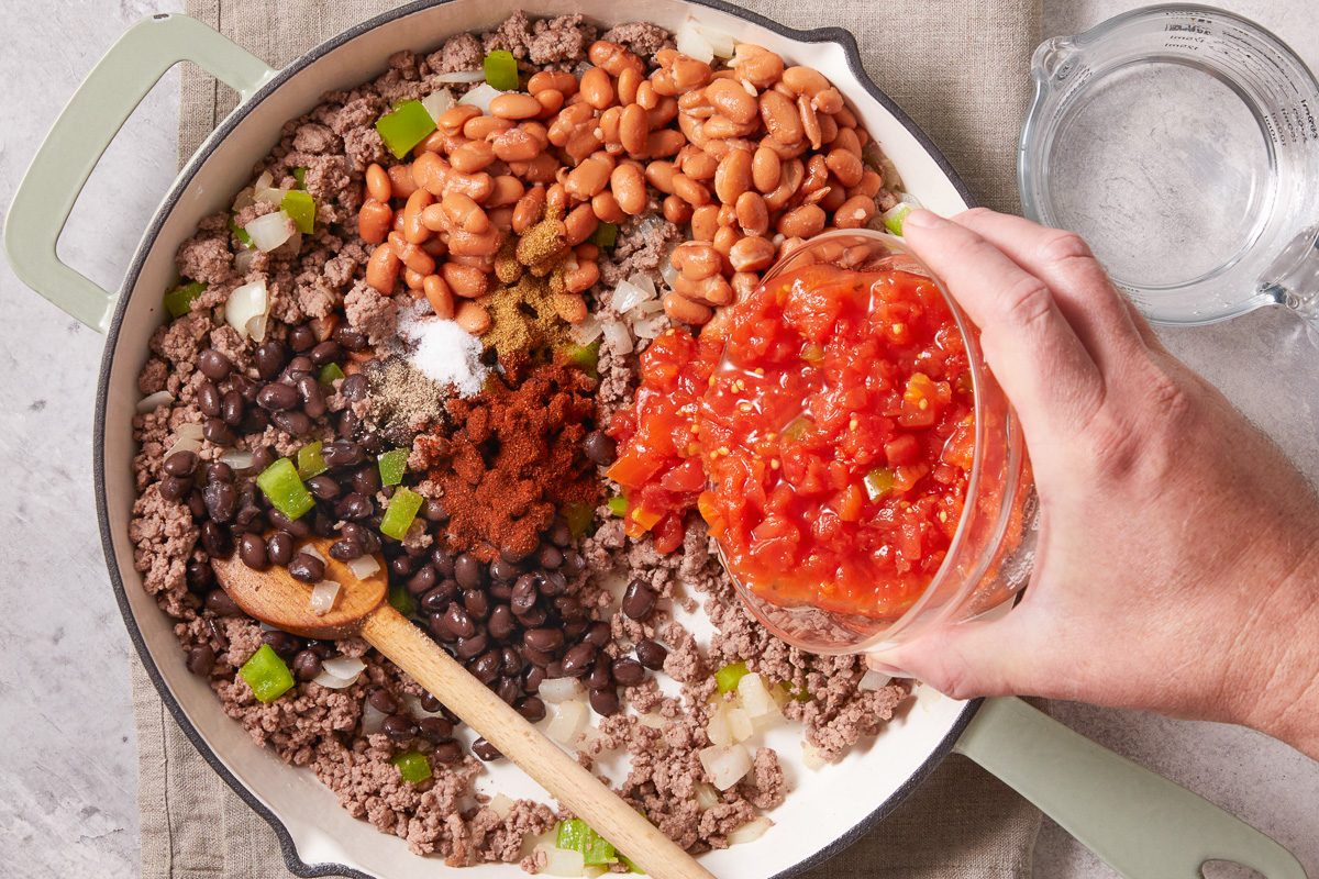 adding diced tomatoes to pan